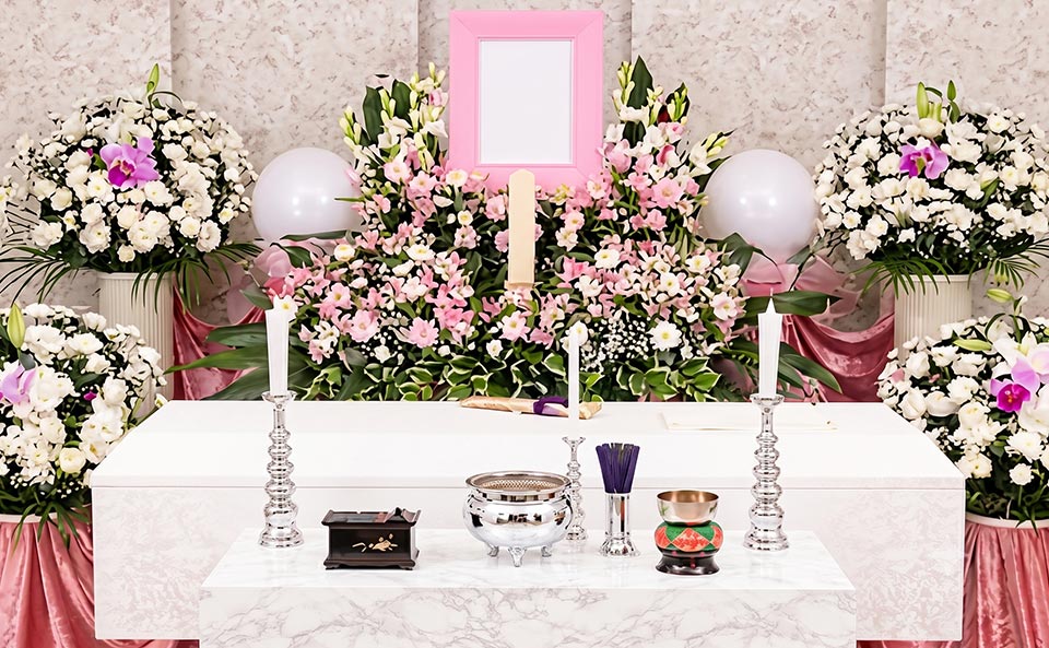 一日葬プランの参考イメージ。ピンクと白の生花で彩られた祭壇。中央には遺影額が置かれ、手前の祭壇上には仏具が並んでいます。